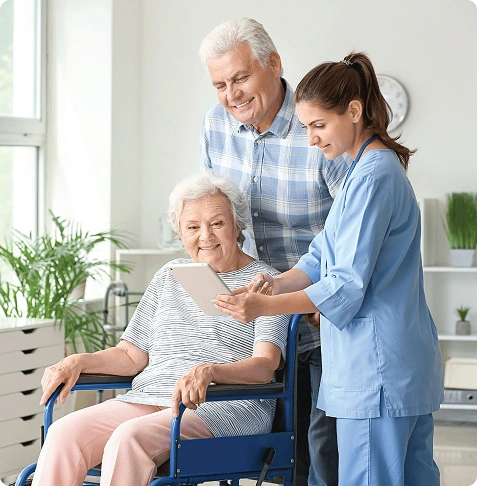 A nurse showing a tablet to elderly patients in a bright room.