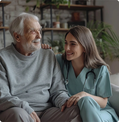 A nurse and elderly man share a warm moment together.