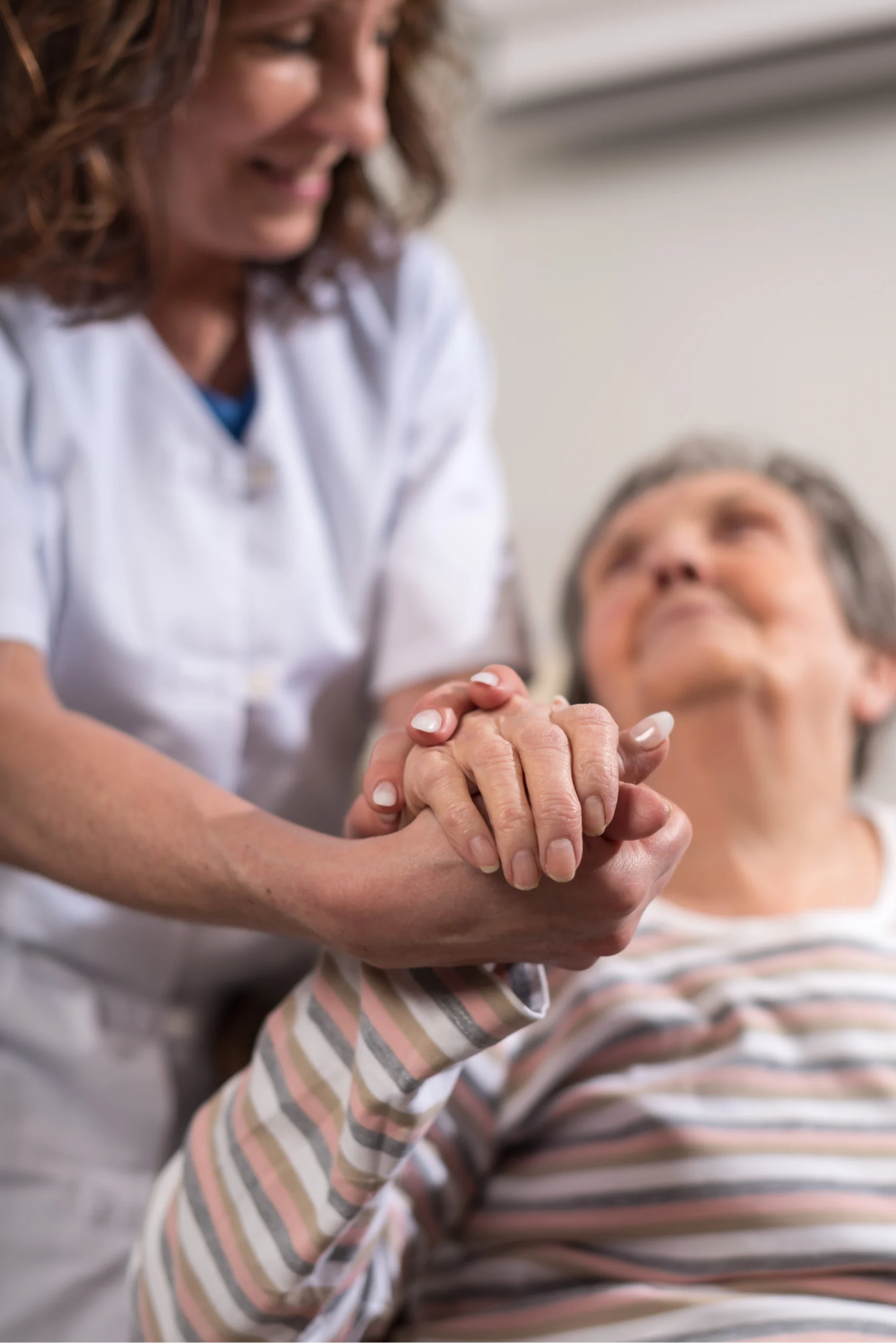 A nurse holding an elderly patient's hand, showing care and support.
