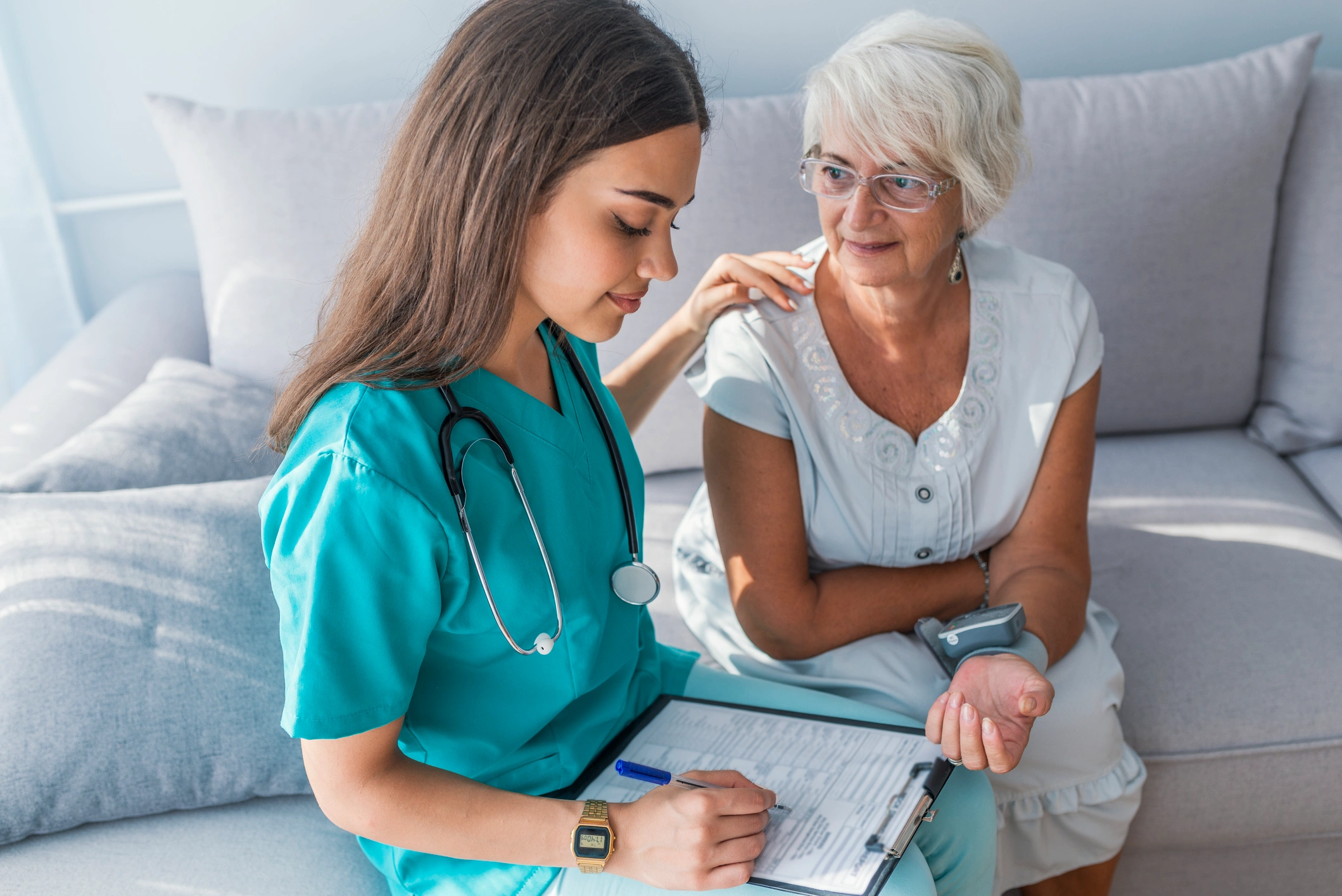 A nurse consulting with an elderly woman in a home setting.